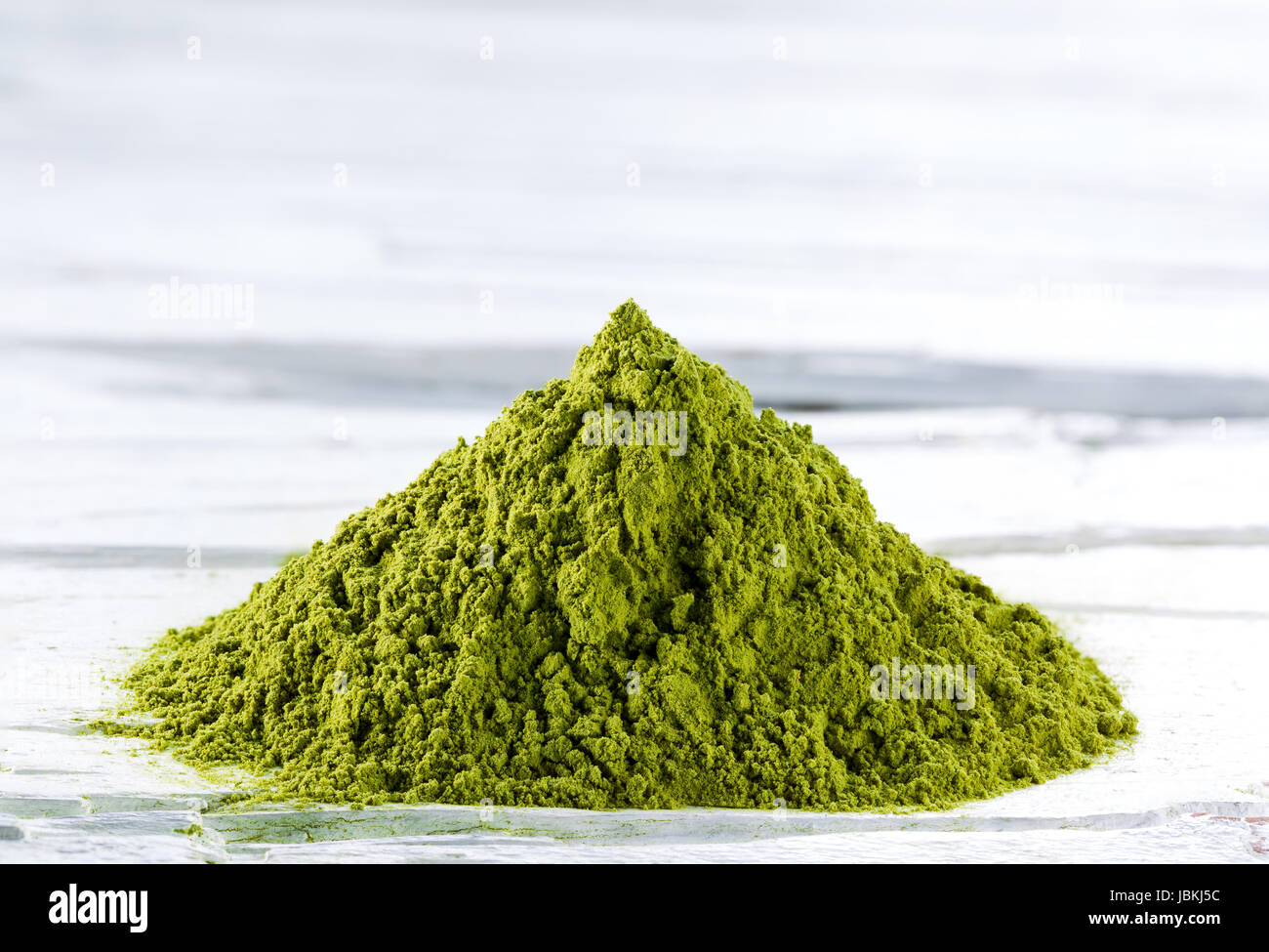 Heap of green matcha tea powder on white weathered wooden background Stock Photo
