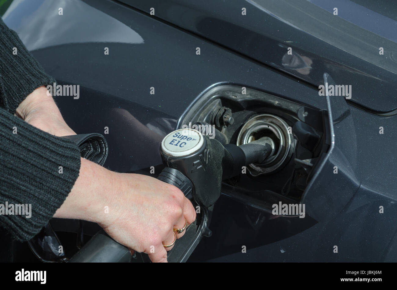 Frauenhand beim Betanken eines Sportwagen mit Kraftstoff E 10 Stock Photo