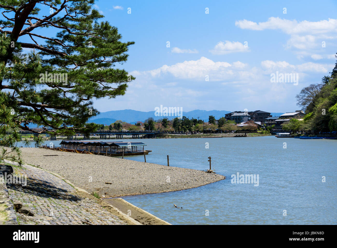 Katsura river at Arashiyama, sightseeing boats  moored at the riverbank and Togetsukyo bridge in the background. Stock Photo