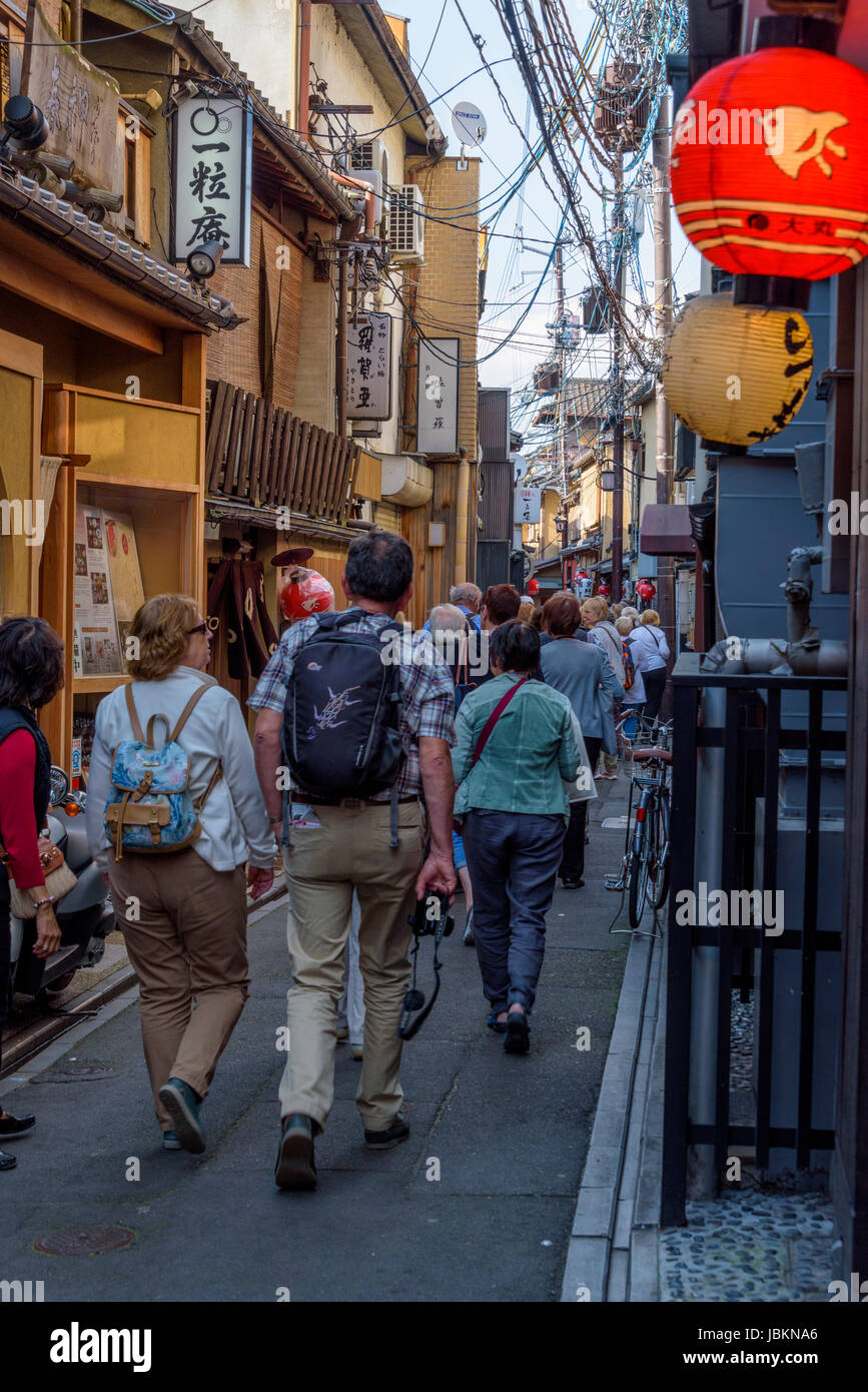 Crowd of european and asian tourists walking through a narrow street, early evening Gion, Kyoto. Stock Photo