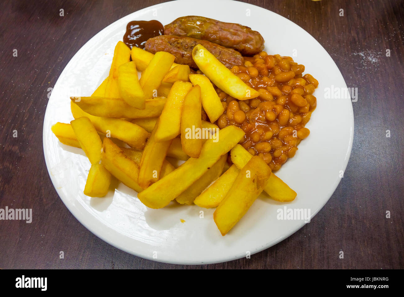 A traditional inexpensive café meal, sausage, chips baked beans and brown sauce Stock Photo Alamy
