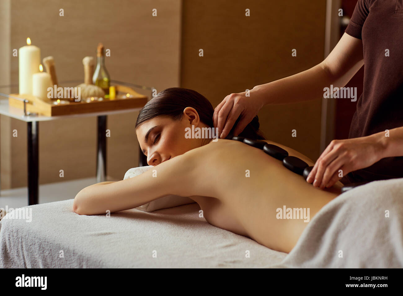 Massage stones on  back of a woman at the spa salon Stock Photo