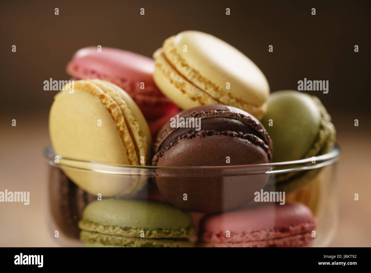 assorted macarons in glass bowl on wood table Stock Photo