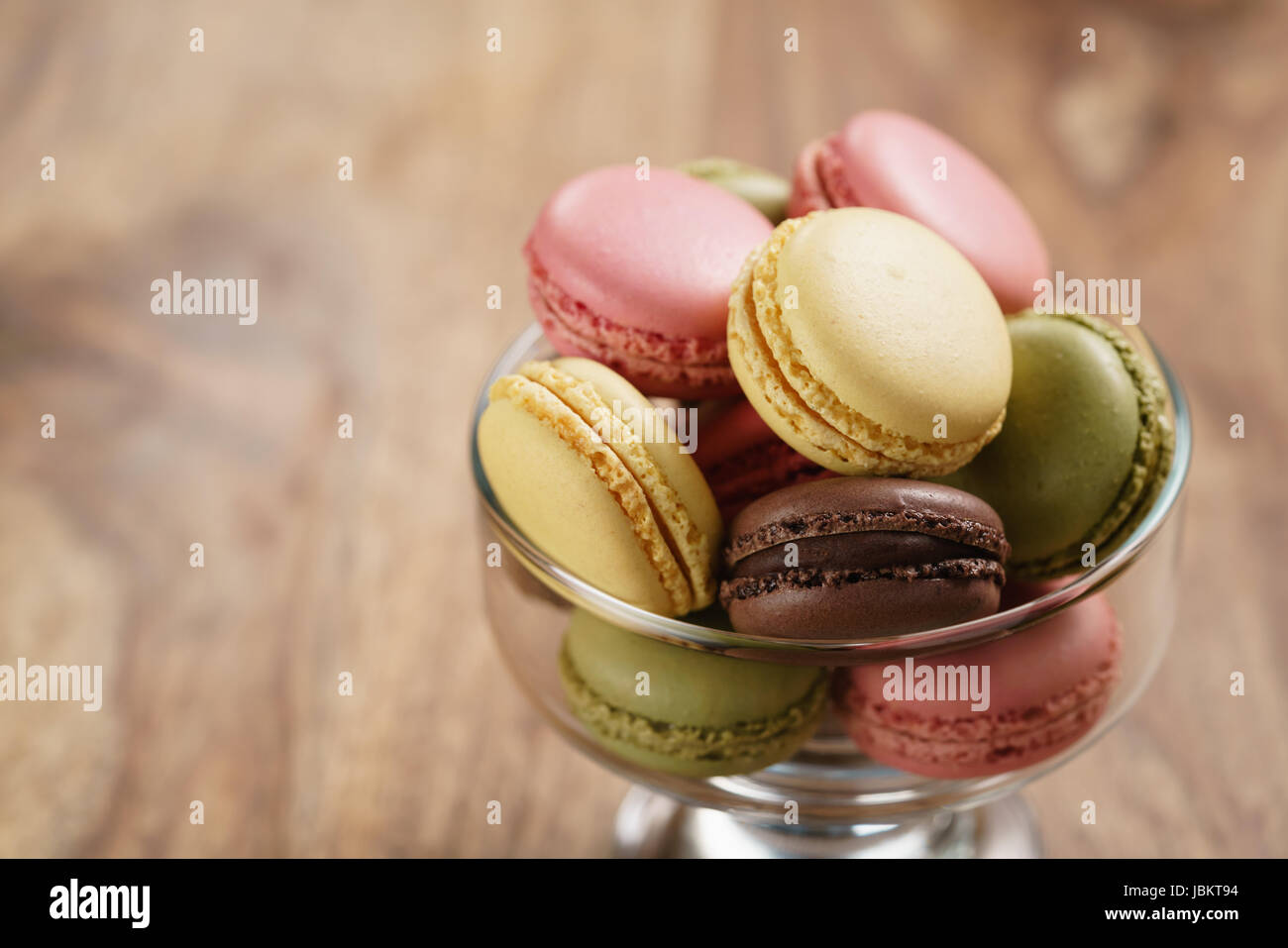 assorted macarons in glass bowl on wood table Stock Photo