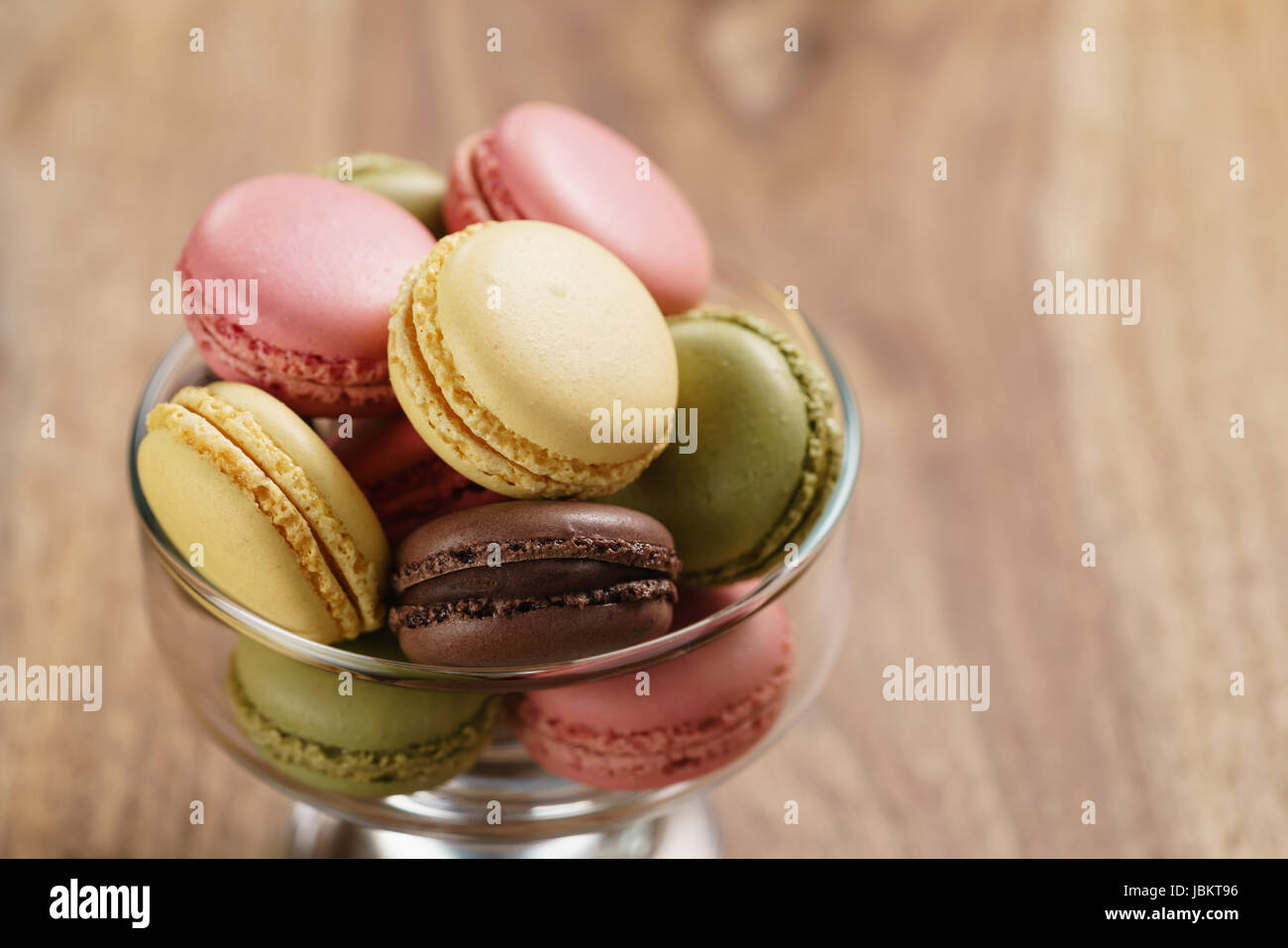 assorted macarons in glass bowl on wood table Stock Photo