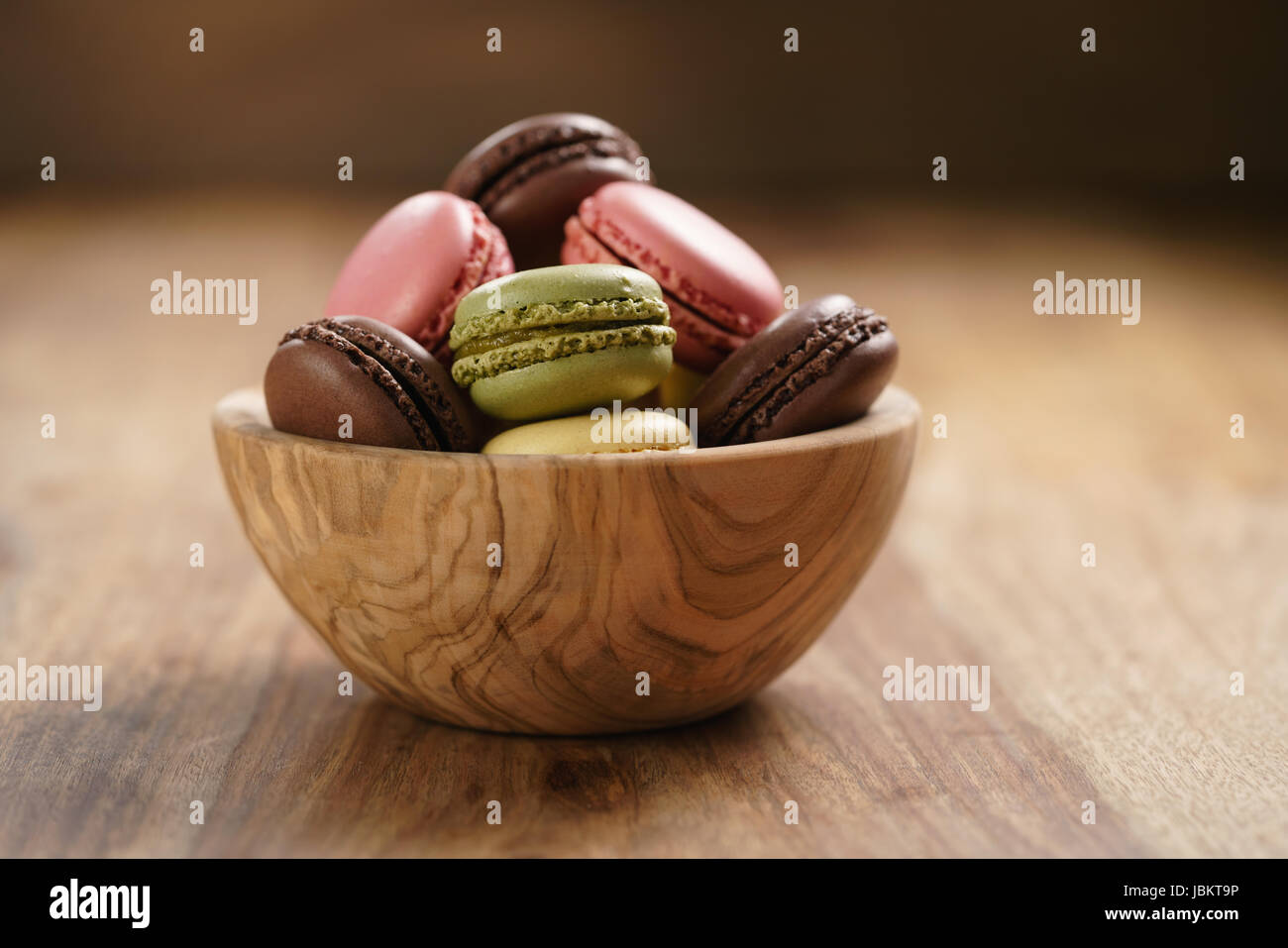 assorted macarons in wood bowl on wooden table Stock Photo