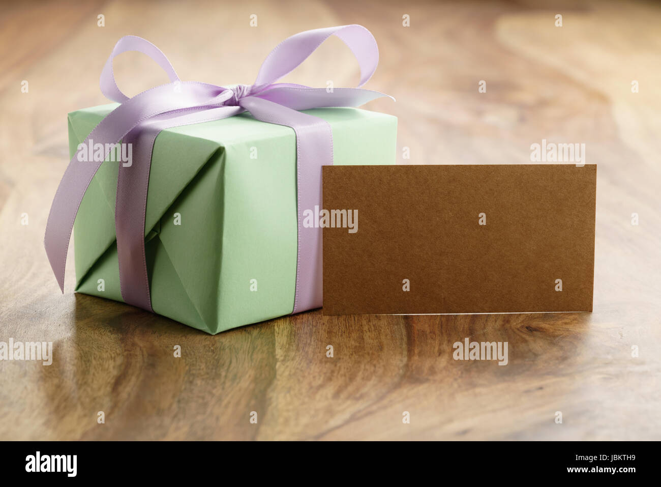 green paper gift box with purple ribbon bow on old wood table with ...