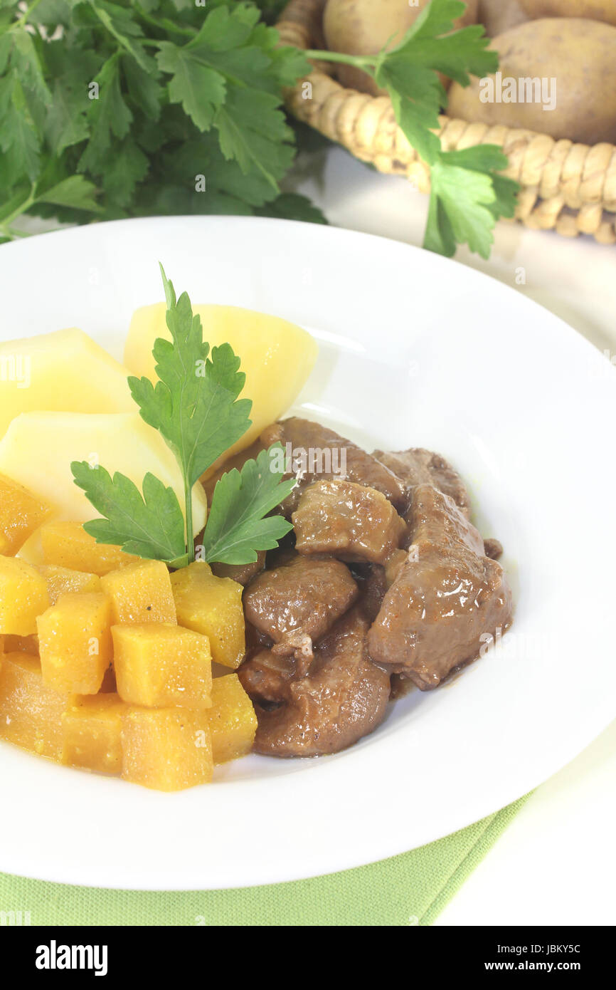 Wildgulasch mit Steckrüben und Petersilie auf hellem Hintergrund Stock ...