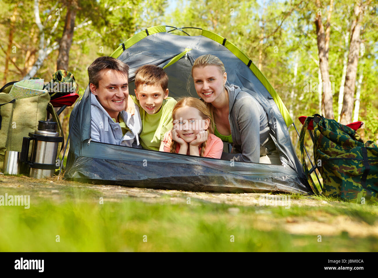 Portrait of family of travelers in tent looking at camera in the forest ...