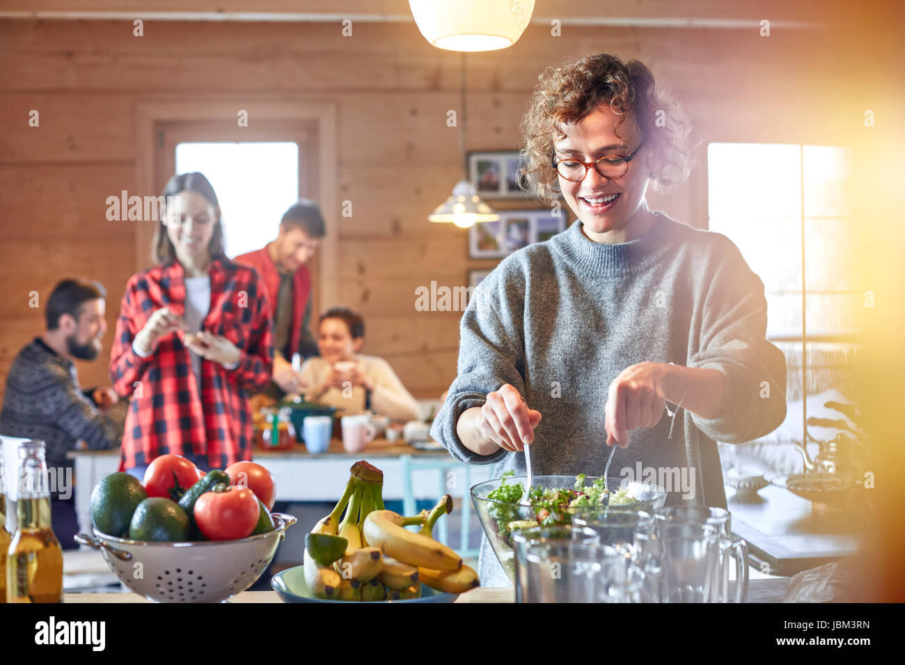 Woman tossing salad for friends in cabin Stock Photo