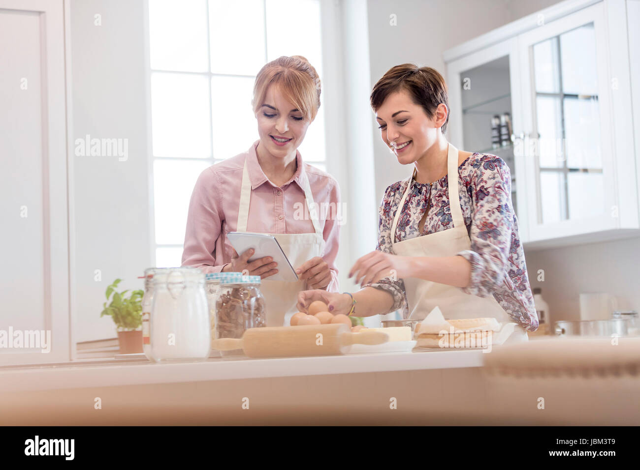 Female caterers with digital tablet baking in kitchen Stock Photo