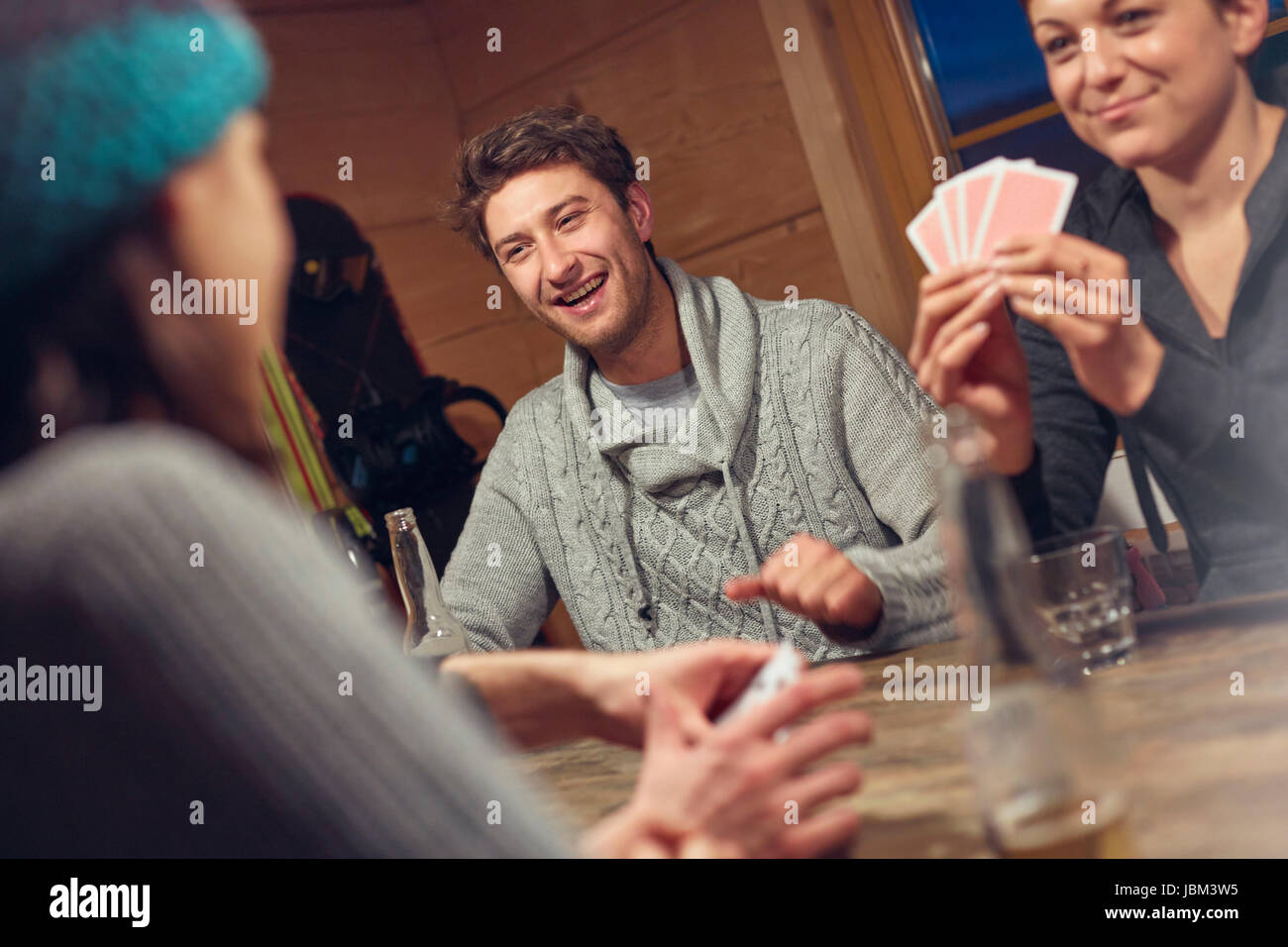 Friends playing cards at table in cabin Stock Photo