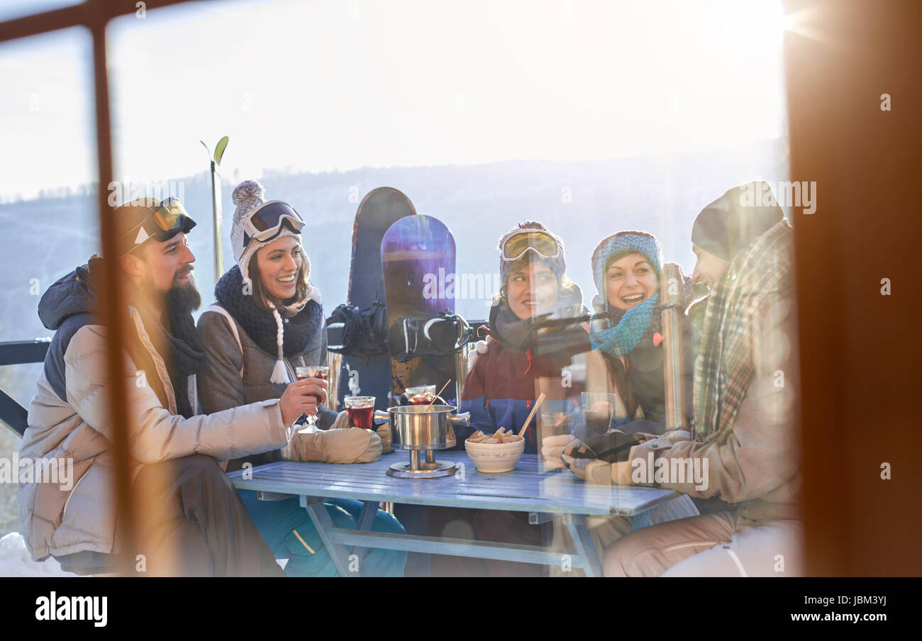Snowboarder friends drinking and eating at balcony table apres-ski Stock Photo
