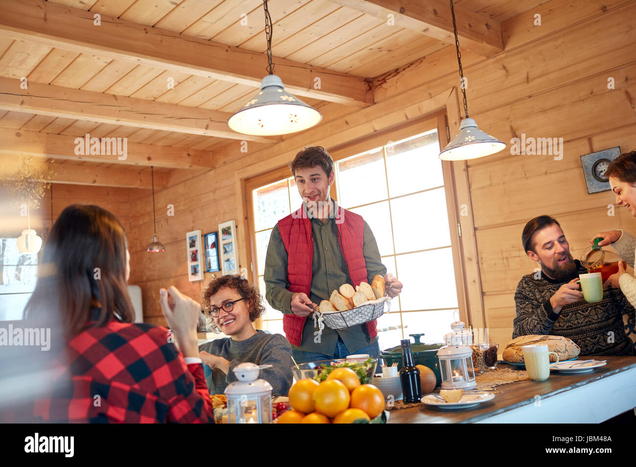 Friends serving and eating food in cabin Stock Photo