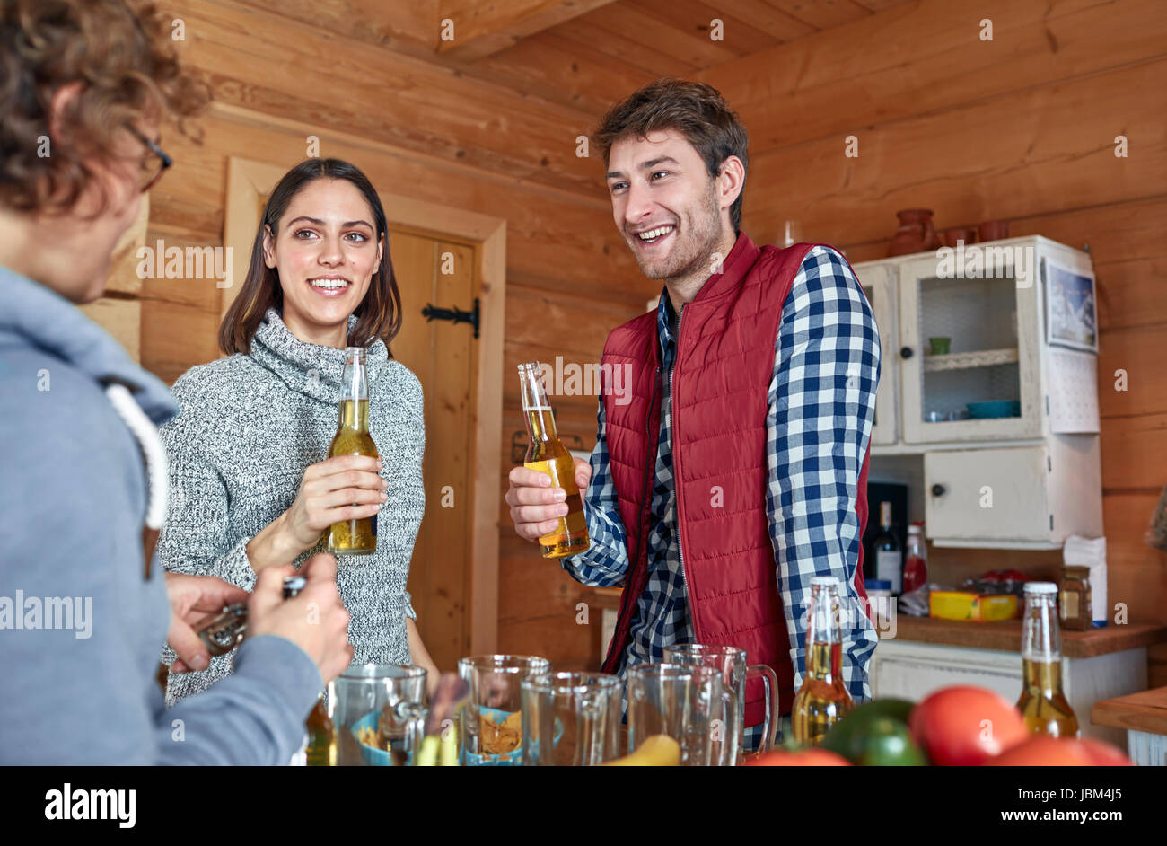 Friends drinking beer and hanging out in cabin kitchen Stock Photo