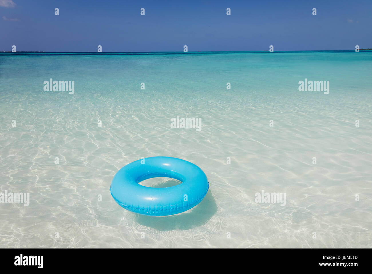 Blue inflatable ring floating in tropical ocean Stock Photo