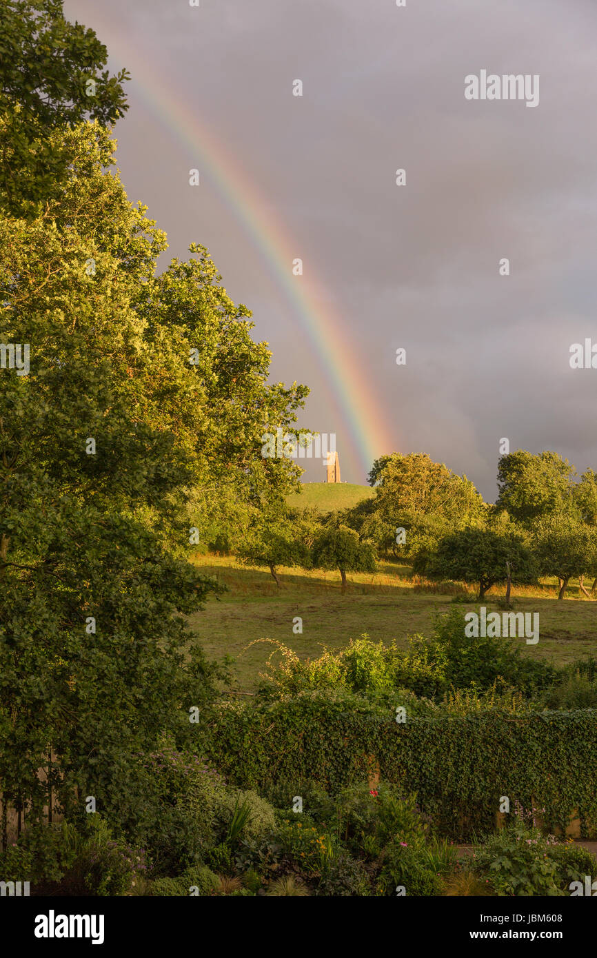 Rainbow behind lush green trees in countryside Stock Photo