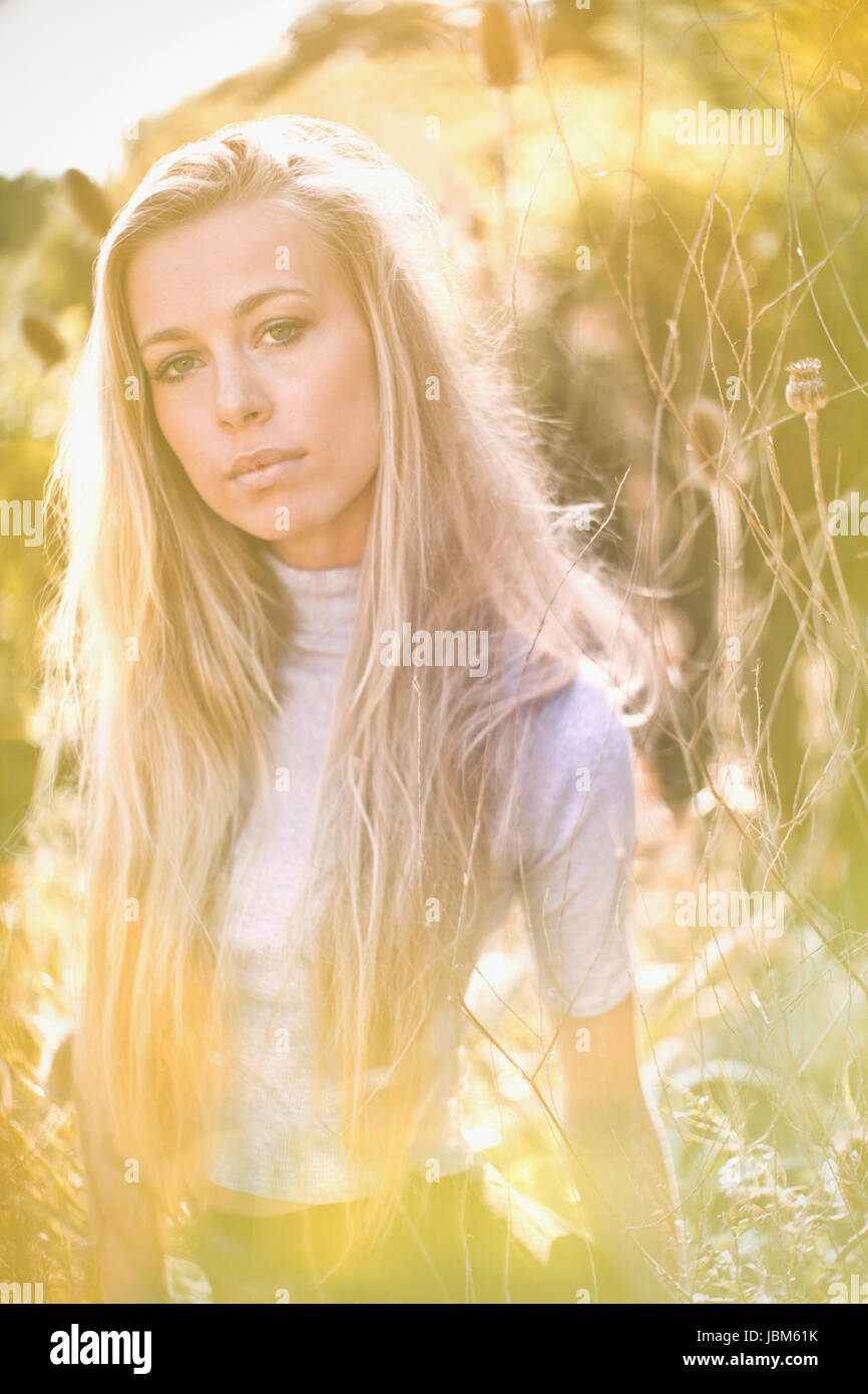 Portrait serious, beautiful blonde teenage girl in sunny field Stock Photo