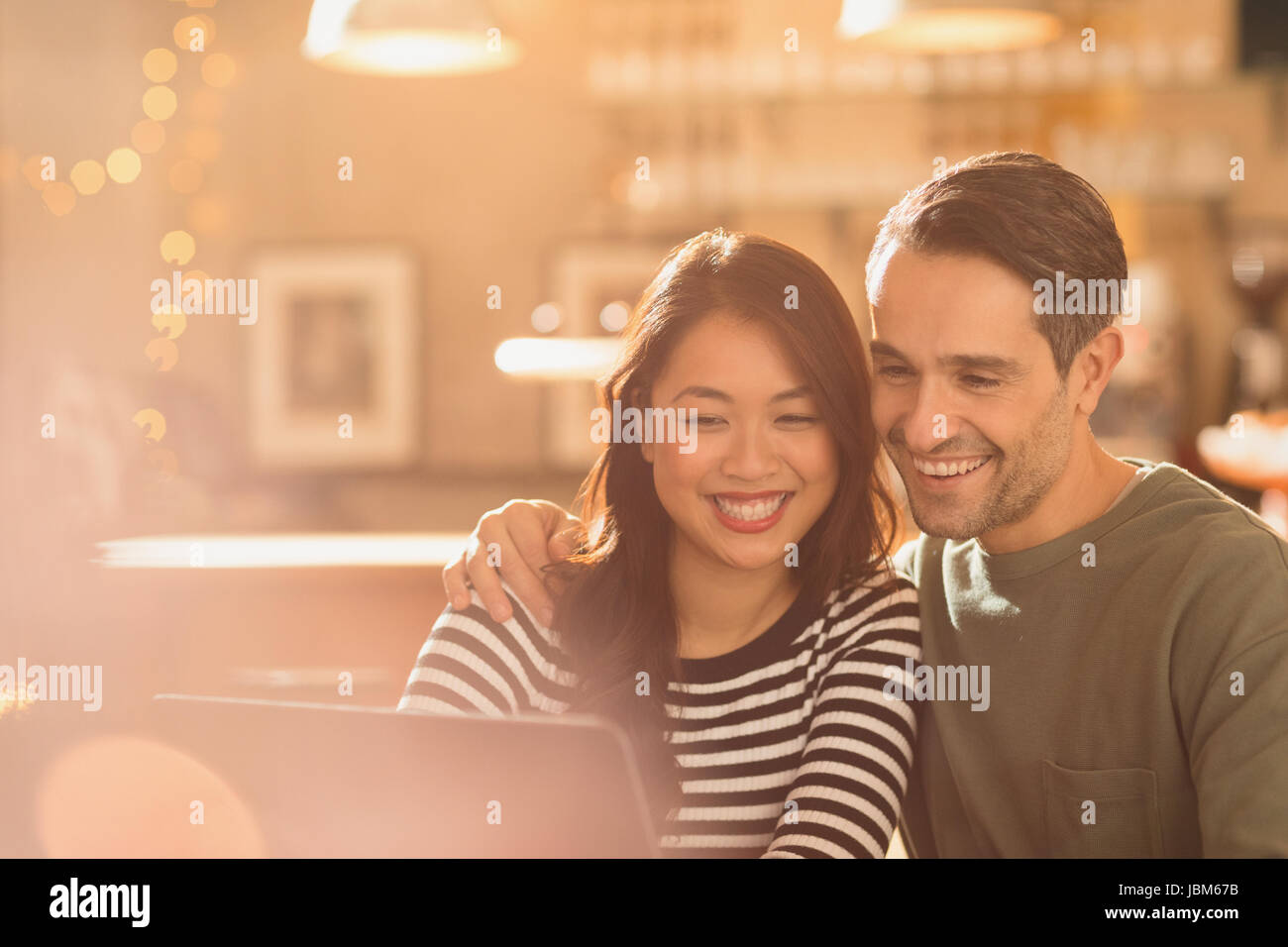 Smiling couple video chatting at laptop in cafe Stock Photo