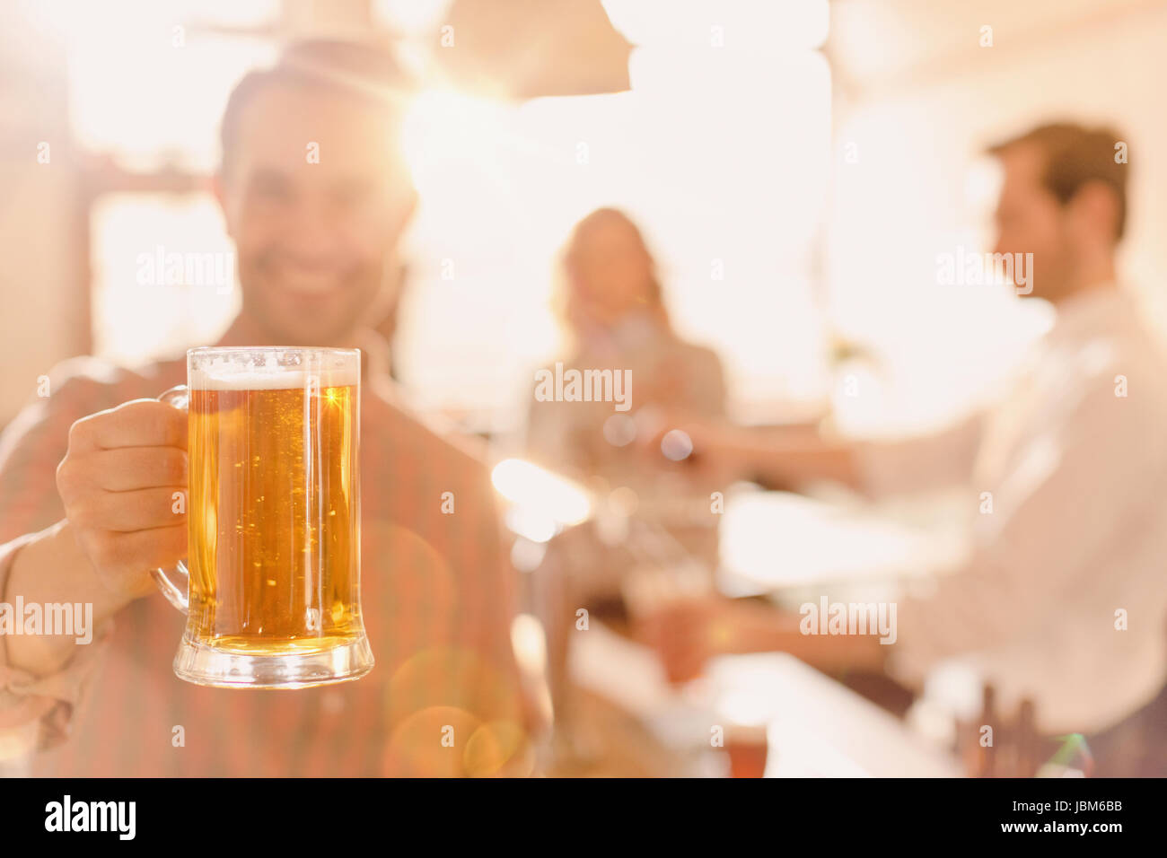 Portrait smiling man holding beer stein at brightly lit bar Stock Photo