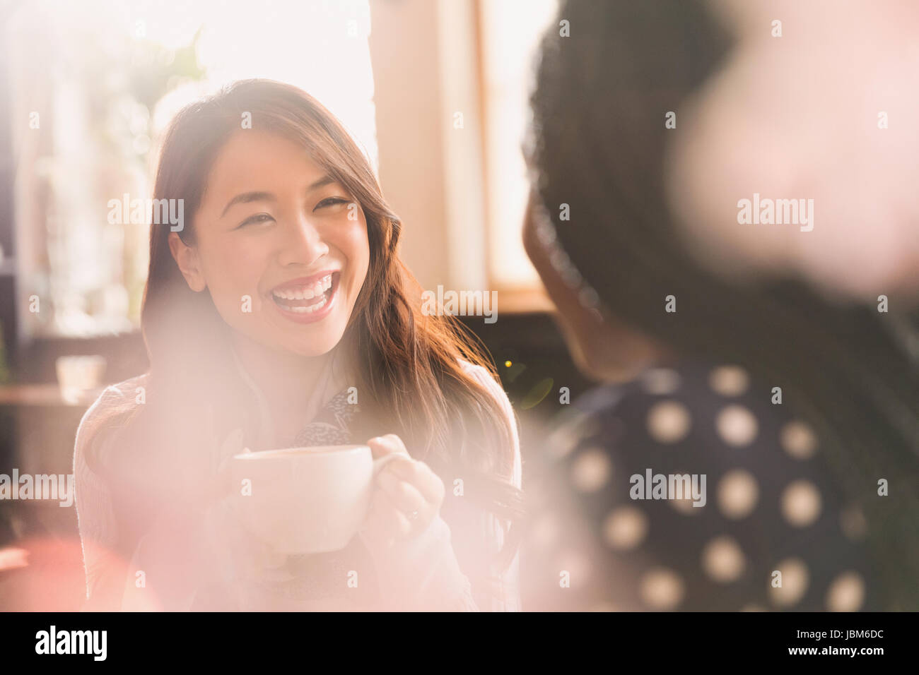Laughing women talking and drinking coffee in cafe Stock Photo