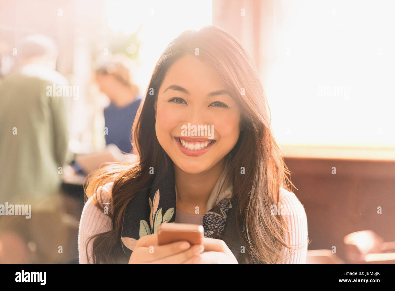 Portrait smiling Chinese woman texting with cell phone in cafe Stock Photo