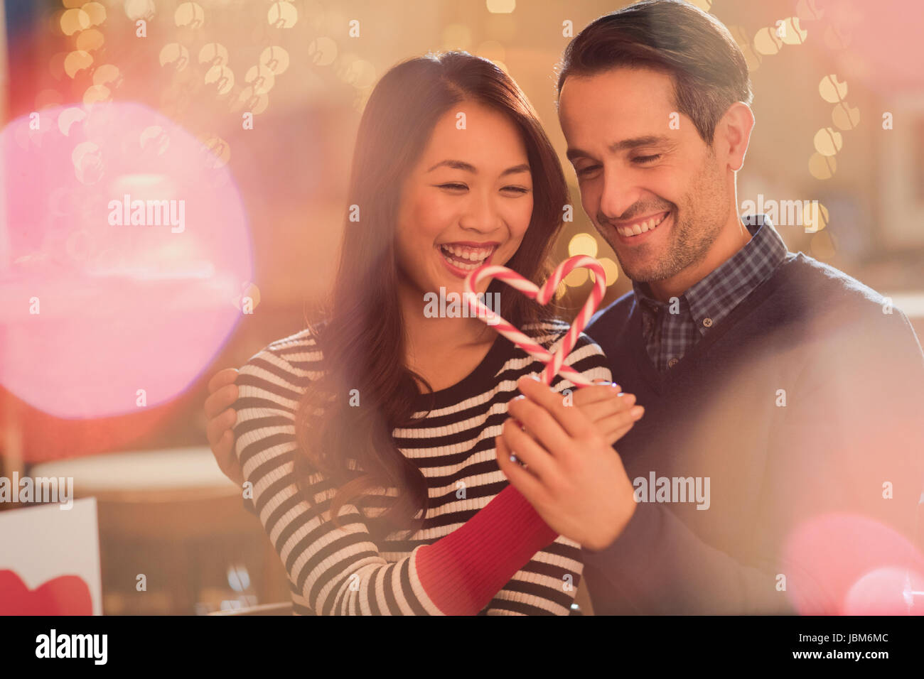 Couple holding heart-shape candy canes Stock Photo