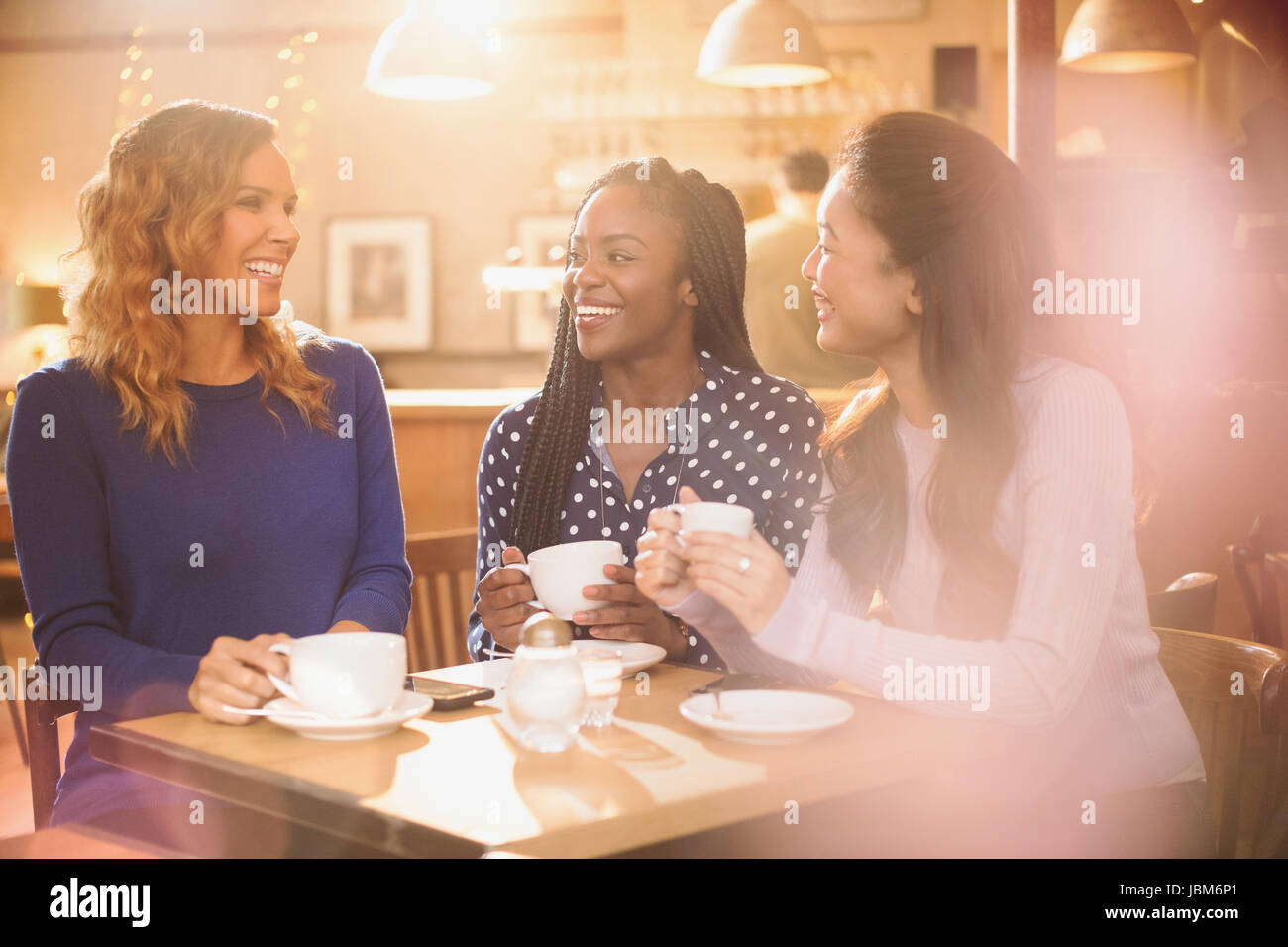 Women friends drinking coffee and talking at cafe table Stock Photo