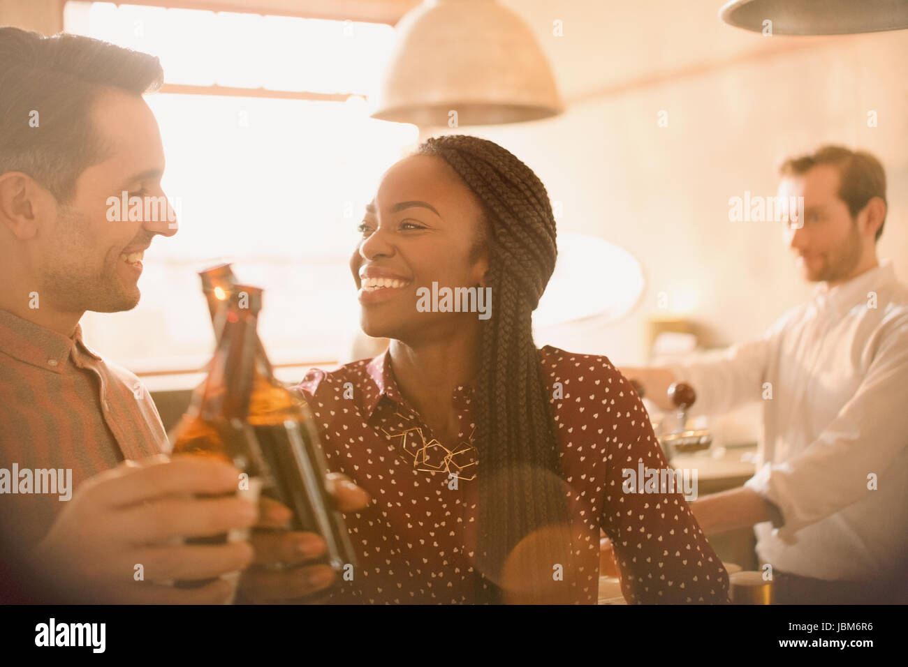 Smiling couple toasting beer bottles in bar Stock Photo