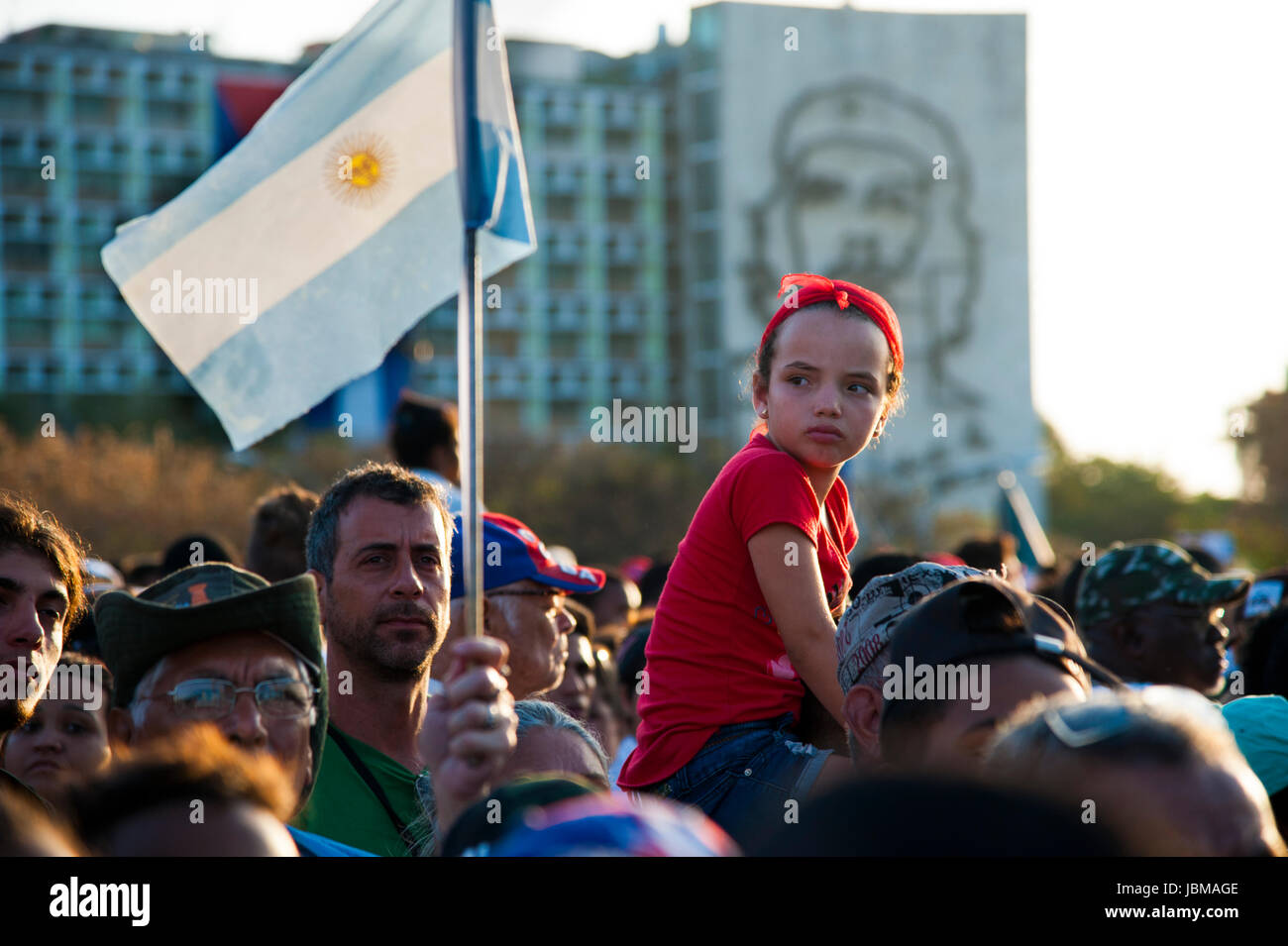 Young Cuban girl rides on man's shoulder at May Day parade  in Havana, Cuba's Revolutionary Square.  A figure of revolutionary hero Che Guevara. Stock Photo