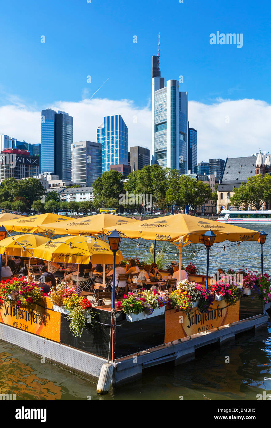 Bootshaus floating restaurant on the banks of the River Main with the skyline of financial district behind, Frankfurt, Hesse, Germany Stock Photo