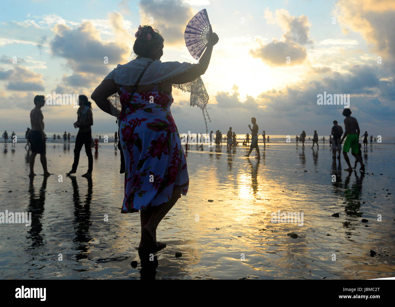 A woman dances with a fan on the beach at sunset at the 2015 Envision Festival, a transformational festival on Costa Rica's Pacific Coast. Stock Photo