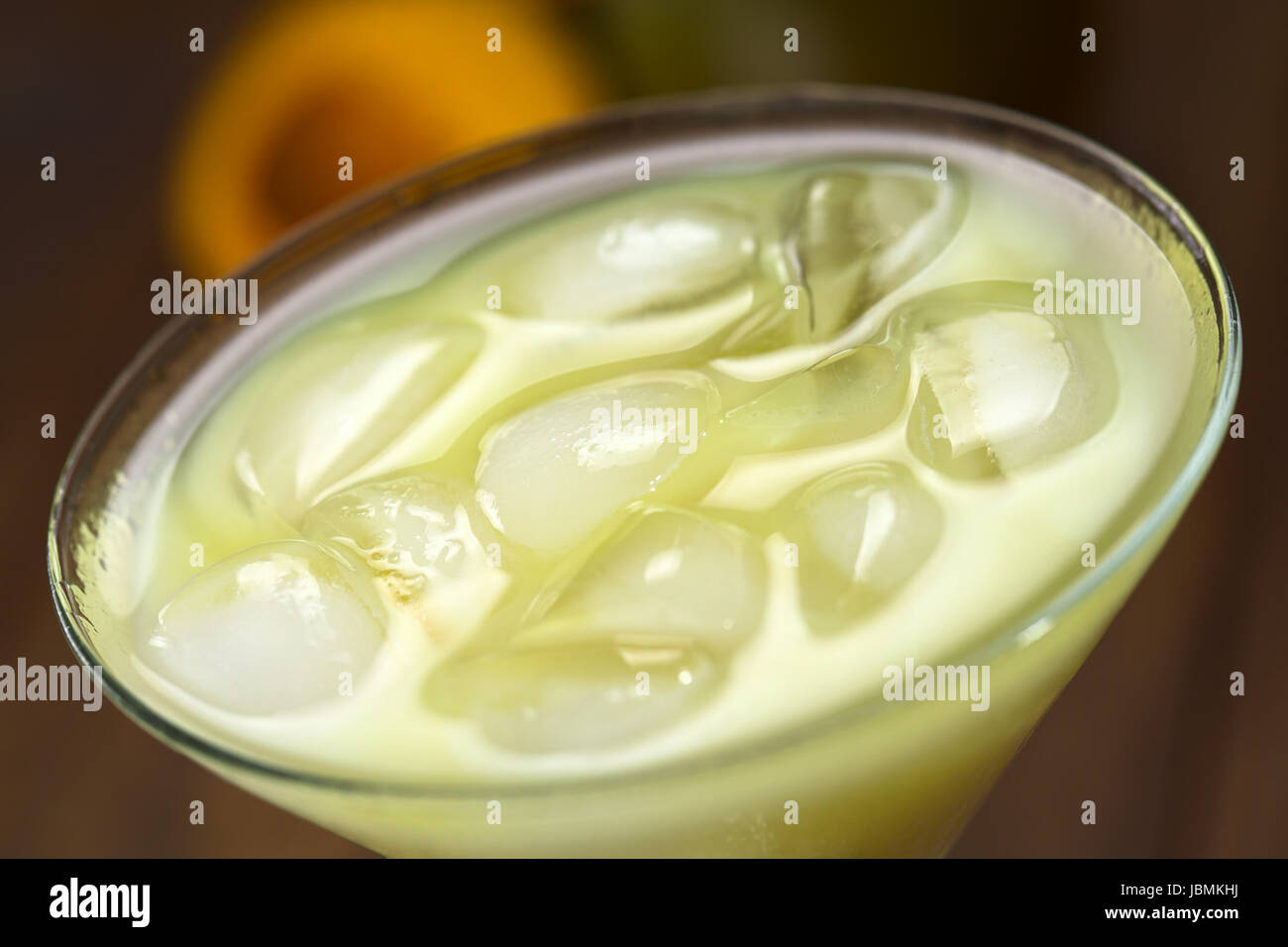Peruvian cream liqueur made of lucuma fruit served in cocktail glass with ice cubes (Selective Focus, Focus in the middle of the ice cubes) Stock Photo