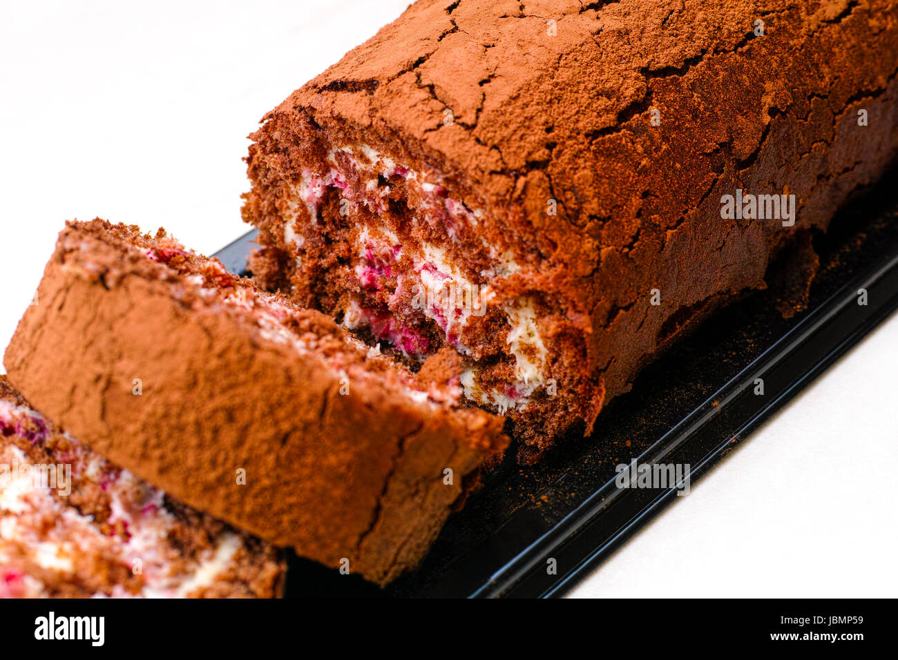 Slices of tasty chocolate sponge cake roll with cream. White background. Stock Photo