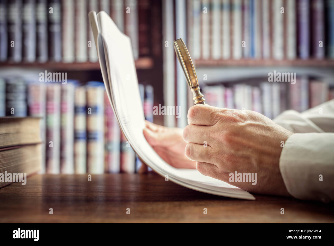 Businessman reading documents with magnifying glass concept for analyzing a finance agreement or legal contract Stock Photo