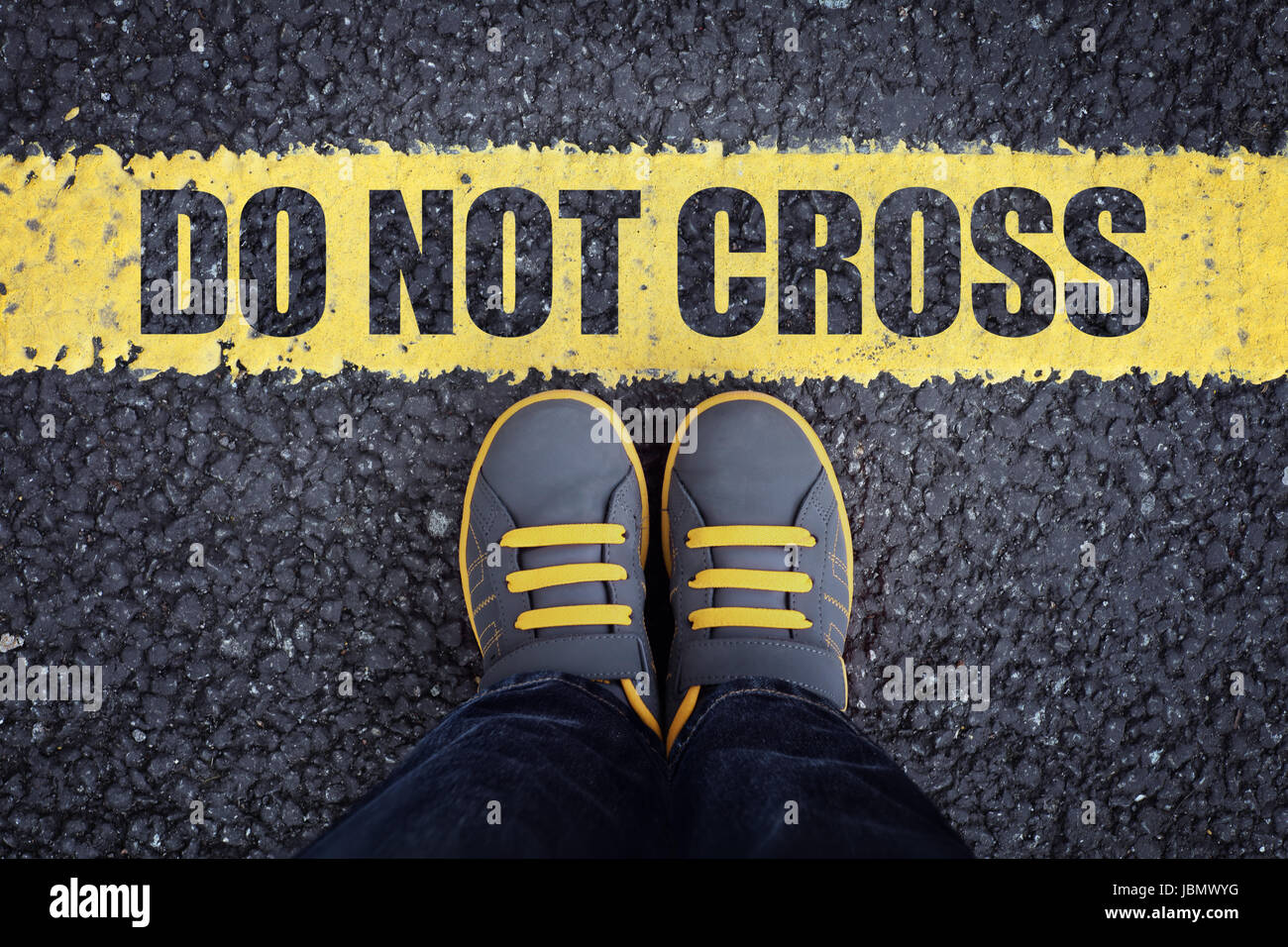 Do not cross line child in sneakers standing next to a yellow line with restriction or safety warning Stock Photo