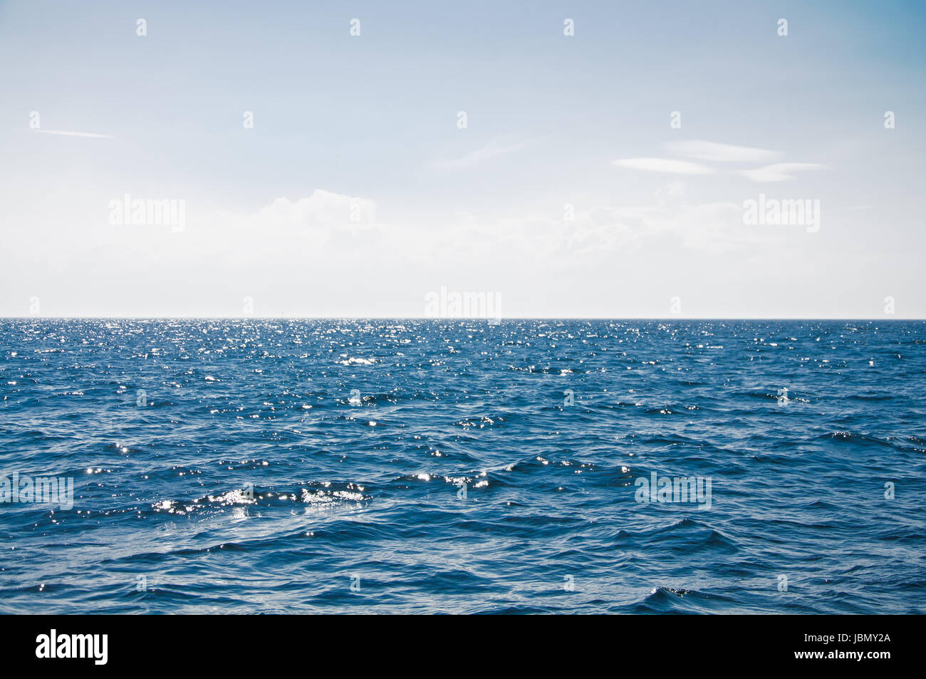 Blue sea with waves and cloudy blue sky Stock Photo - Alamy