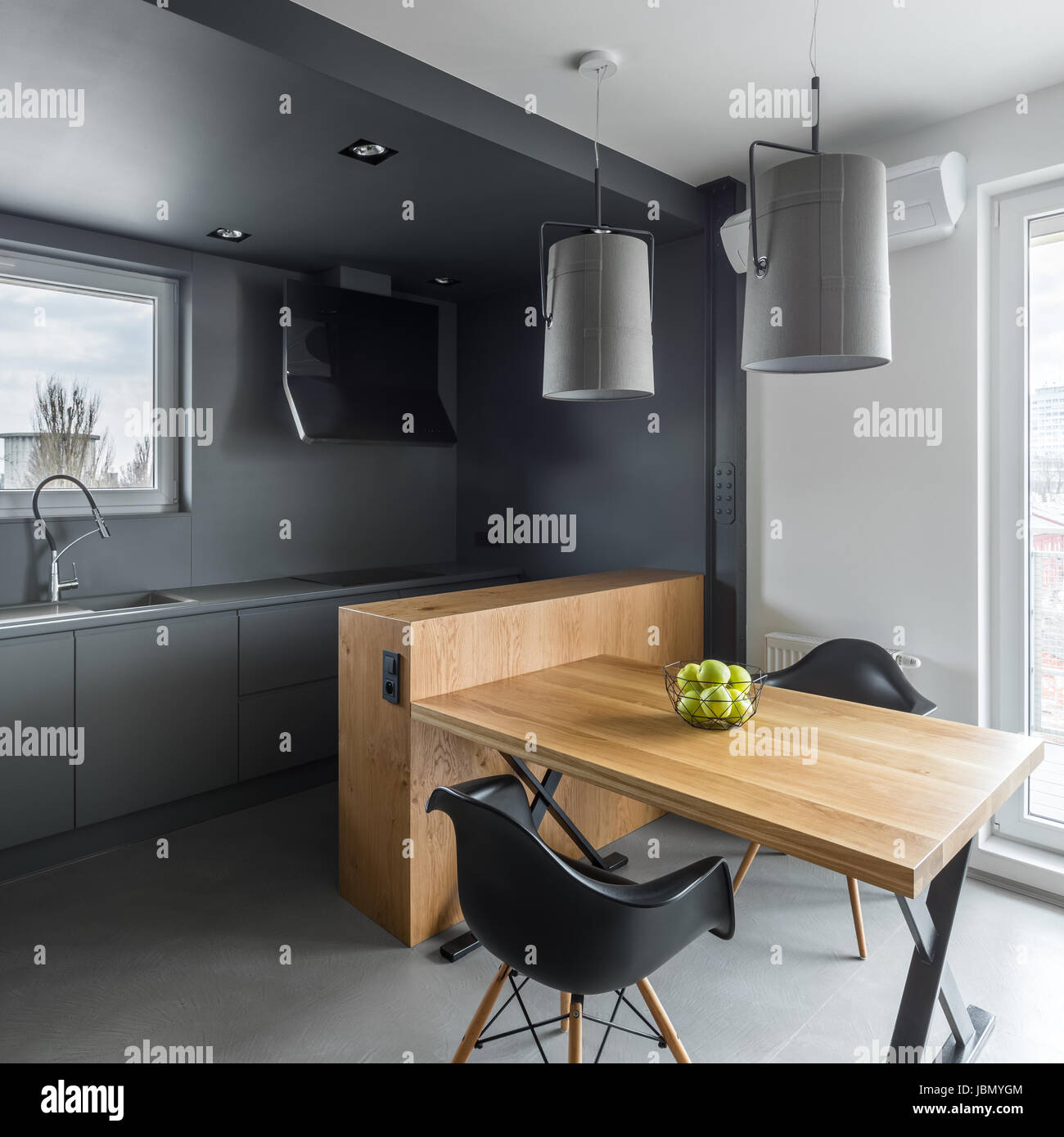 Dark gray kitchen with island, wooden table and black chairs Stock