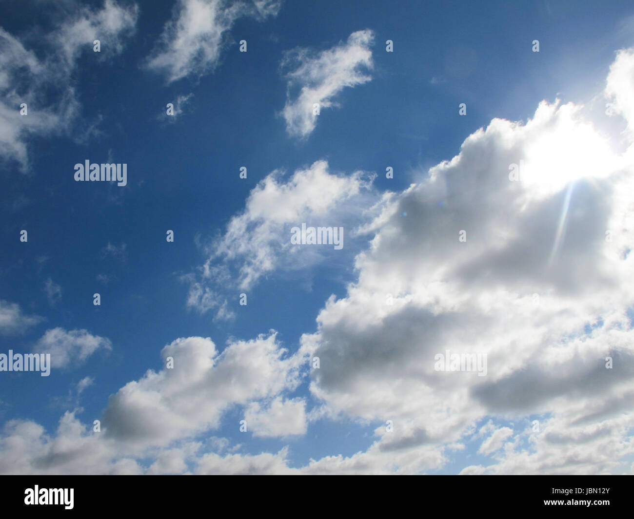 Blue sky with clouds and lens flare from the sun Stock Photo - Alamy