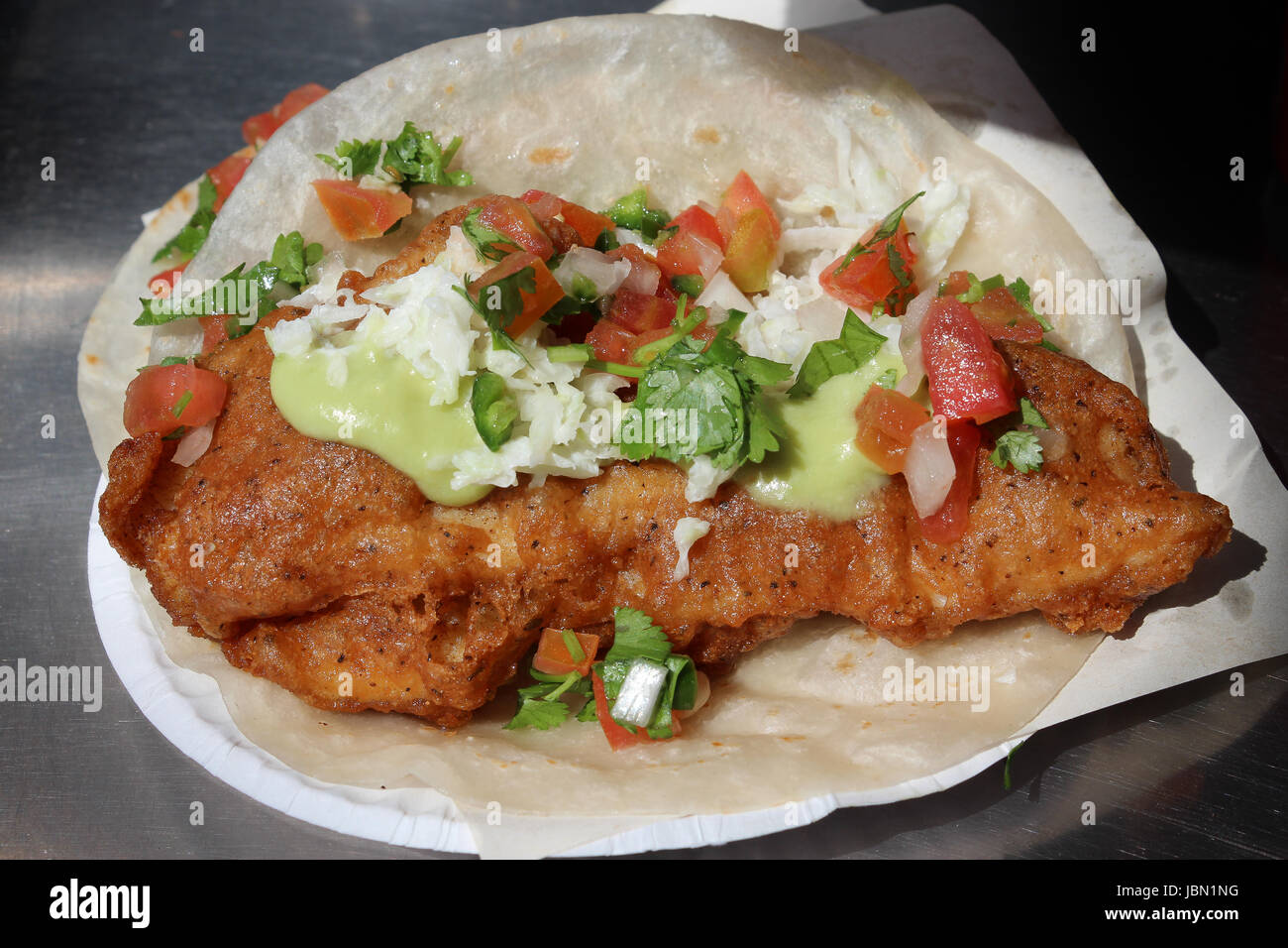Tasty deep-fried fish taco with salsa and crema on flour tortilla, from Mexican street vendor for lunch Stock Photo