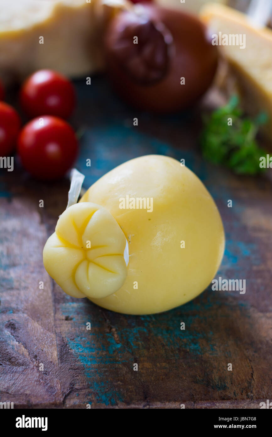 Traditional Italian hard cheese Provolone of Caciocavallo on wooden background Stock Photo