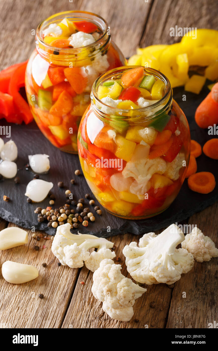 Spicy Homemade Pickled Giardiniera with Peppers, Carrots and Cauliflower close-up in glass jars. Vertical Stock Photo