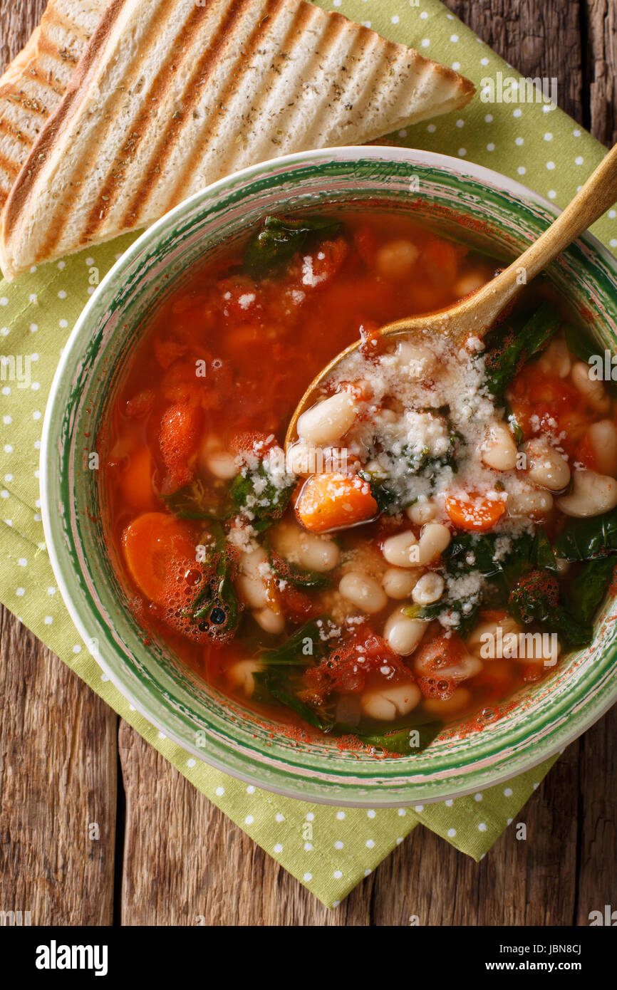 White bean soup with tomatoes, spinach, carrots and parmesan close-up