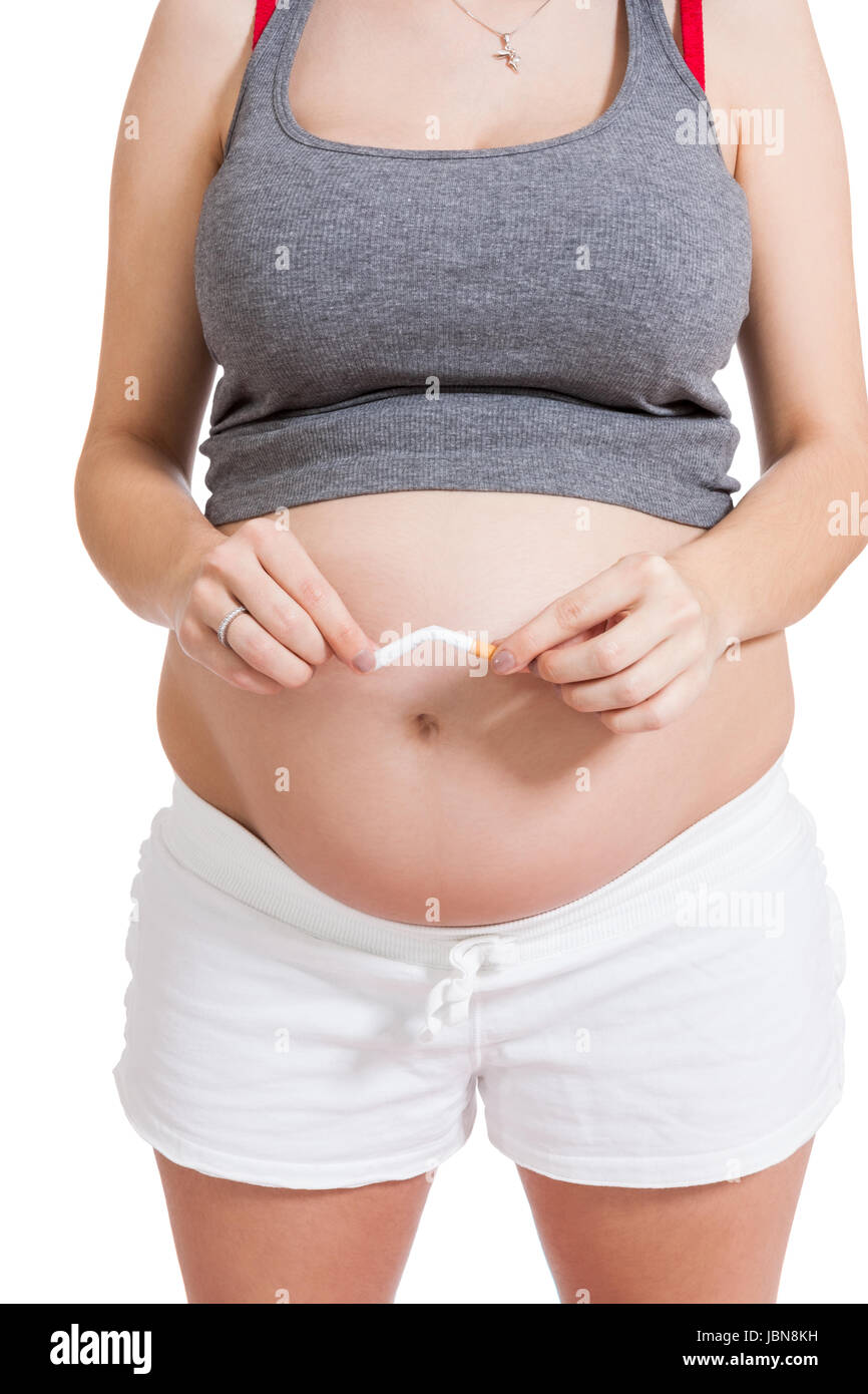 schwangere Frau zerbricht eine Zigarette vor Ihrem Babybauch isoliert vor weißem Hintergrund Stock Photo
