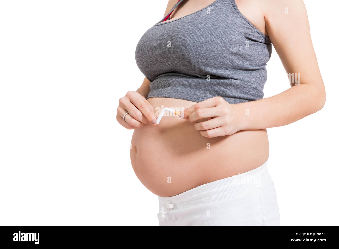 schwangere Frau zerbricht eine Zigarette vor Ihrem Babybauch isoliert vor weißem Hintergrund Stock Photo