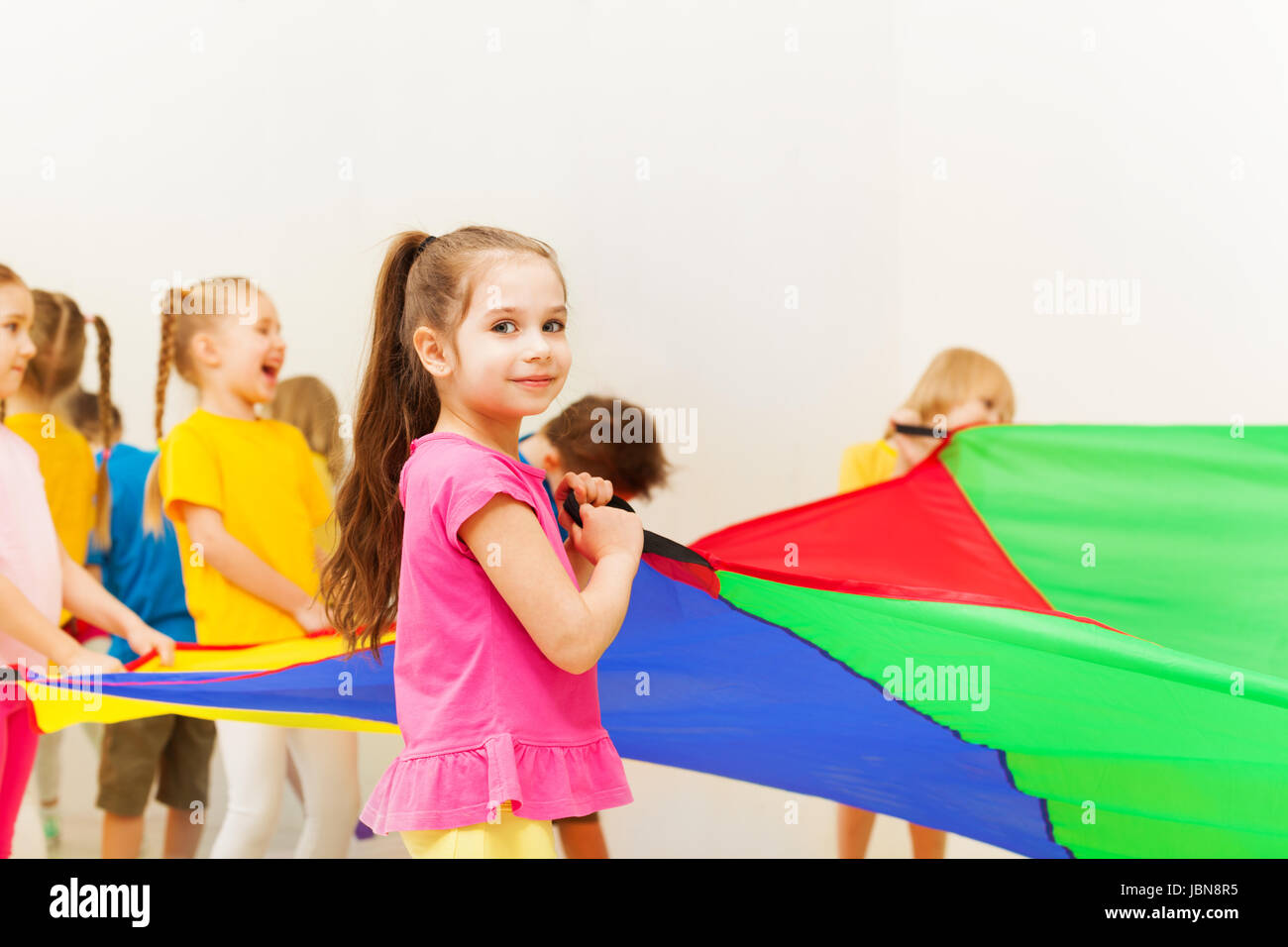 Closeup portrait of seven years old girl waving parachute, playing