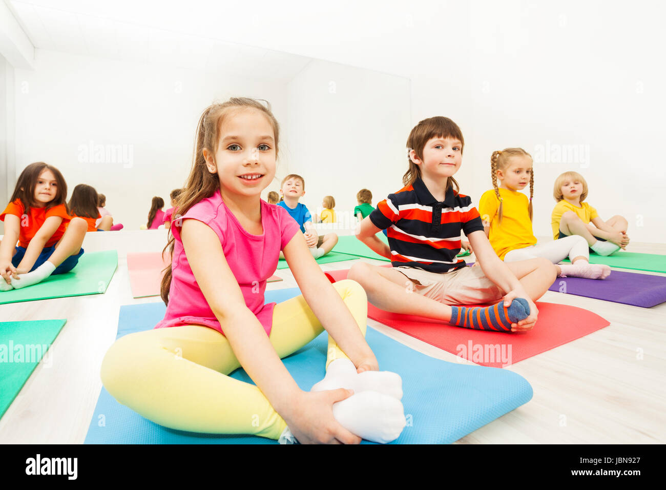 Portrait of beautiful sporty girl doing the butterfly stretch on yoga mat in gym Stock Photo