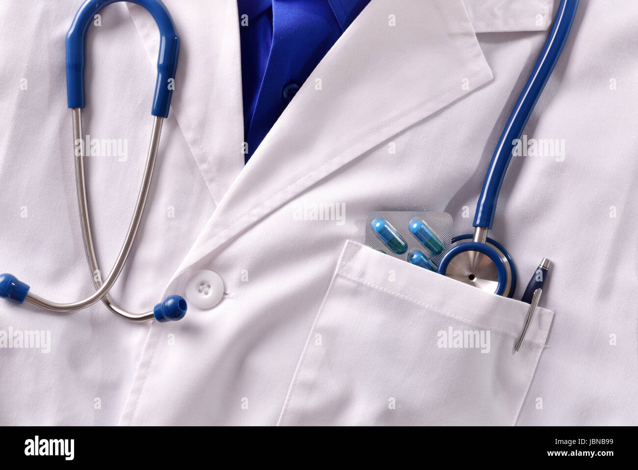 Close up white gown doctor with stethoscope pills and pen in pocket. Horizontal composition. Front view Stock Photo