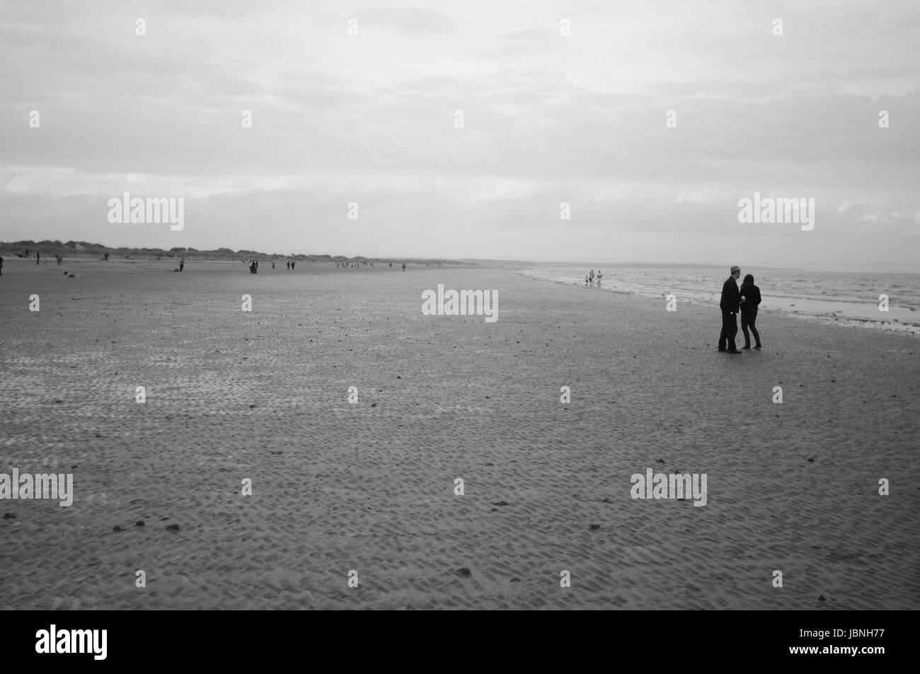 A couple standing on St Andrews beach with the tide out Stock Photo Alamy