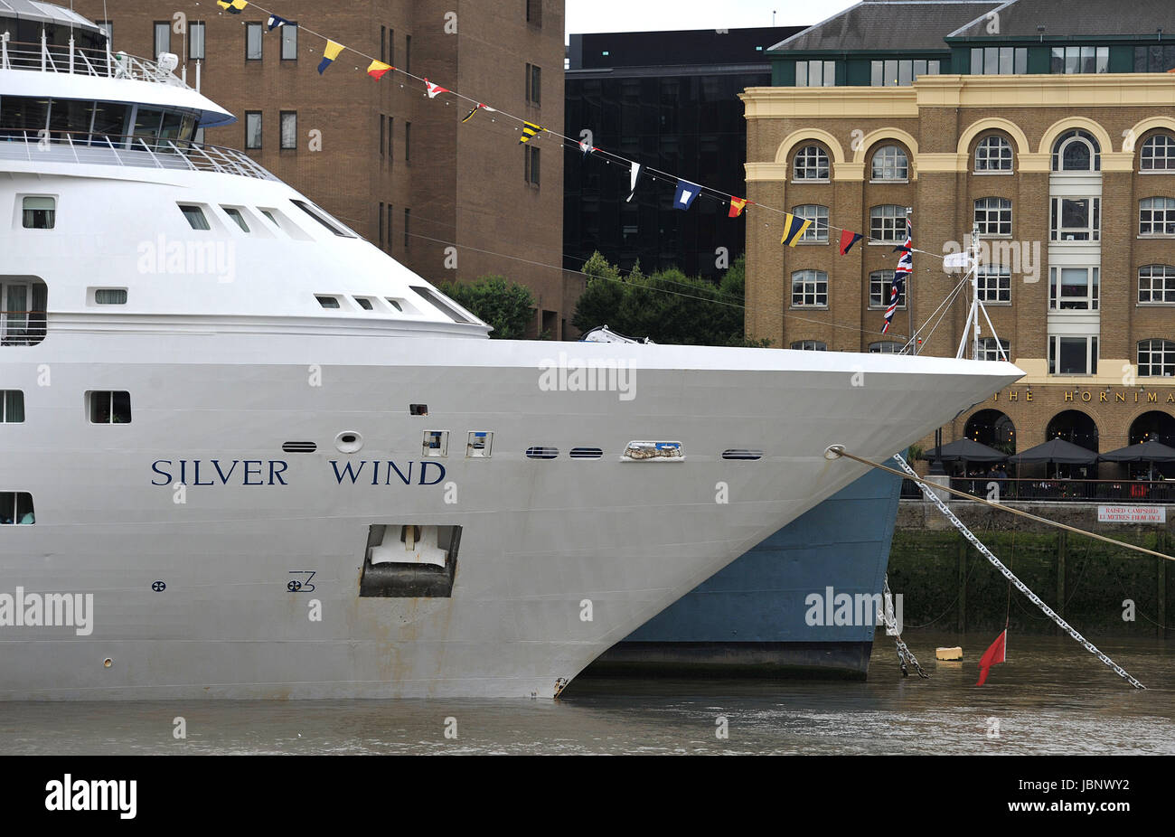 The bow of HMS Belfast juts out behind the bow of Silver Wind a small cruise ship operated by Silversea Cruises, which is berthed next to her on the River Thames, during a stop over in central London. Stock Photo
